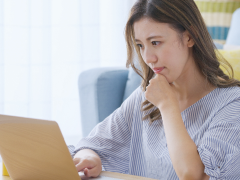 写真：パソコンを見ながら悩んでいる女性